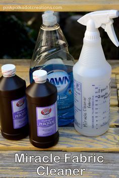 three bottles of fabric cleaner sitting on top of a wooden table