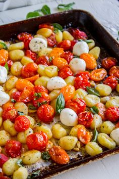 a pan filled with tomatoes and mozzarella on top of a white tablecloth