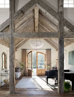 an open living room with a piano and chandelier hanging from the rafters