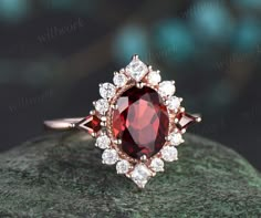 an oval shaped red and white diamond ring on top of a green rock with diamonds around it