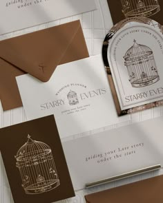 some brown and white business cards are laying on top of each other with a birdcage in the middle