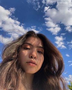 a woman with long brown hair and blue sky in the background