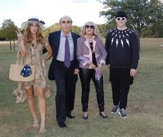 four people dressed up in costumes posing for a photo on the grass with trees in the background