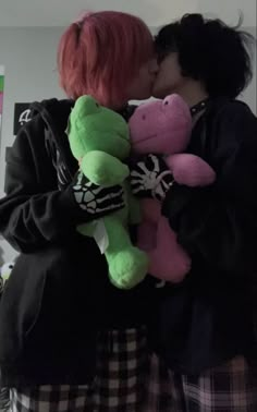 two people kissing each other while holding stuffed animals in front of their faces and one person with pink hair