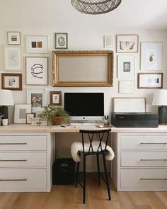 a desk with a computer on it and lots of framed pictures above the top shelf