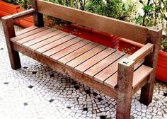 a wooden bench sitting on top of a cobblestone ground next to potted plants