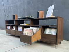 an entertainment center with books and records on the shelves next to a concrete wall in front of a building