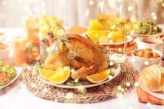 a turkey is sitting on a plate with oranges and other food items around it