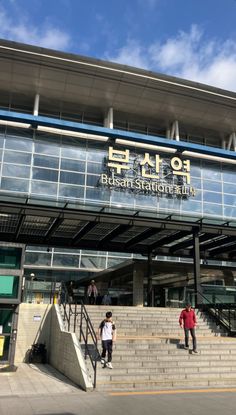 two people are standing on the steps outside an airport terminal building that has stairs leading up to it