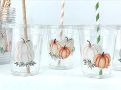 pumpkins painted on glass cups with straws and paper straws in the background