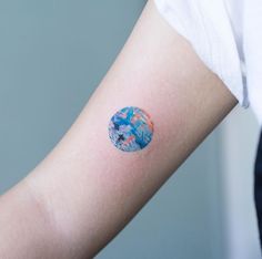 a person's arm with a blue and red circle tattoo on the left forearm