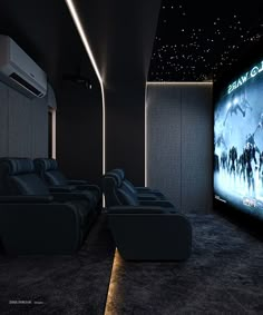 an empty movie theater with black leather seats and a projector screen on the wall