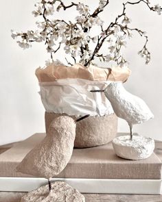 two birds sitting on top of a book next to a vase with flowers in it