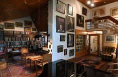 a living room filled with lots of books and pictures on the wall next to a stair case