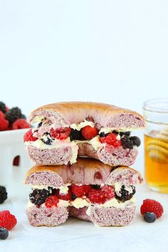 three sandwiches stacked on top of each other with berries and raspberries around them