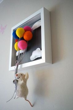 a toy mouse hanging from a wall with balloons attached to it's back end