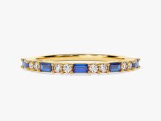 a yellow gold ring with blue and white stones on the sides, set against a plain background