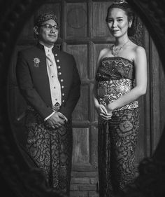 a man and woman standing next to each other in front of a wooden door wearing formal clothing