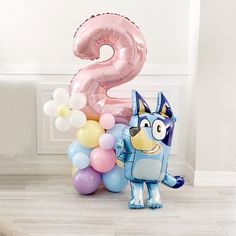 a balloon shaped like a dog standing next to balloons in the shape of number two