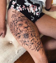 a woman's thigh with flowers and a lion tattoo on her leg, sitting on a couch