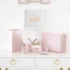 a white desk topped with lots of pink boxes and office supplies on top of it