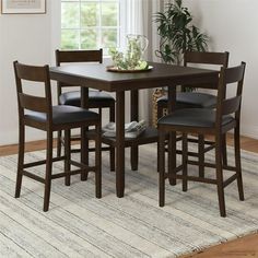 a dining room table with four chairs and a potted plant