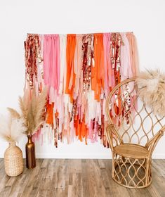 a chair sitting next to a wall covered in pink, orange and white streamers