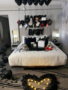 a bed with black and white decorations on the headboard, heart shaped balloons above it