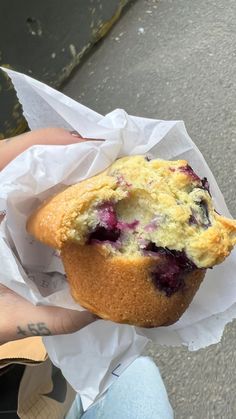 a person holding a muffin with blueberries in it on a paper wrapper