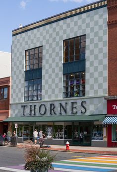 people are walking on the sidewalk in front of shops and stores that are painted multicolored