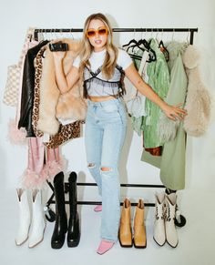 a woman standing in front of a rack with clothes and shoes on it's legs