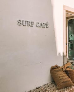 there is a bag sitting on the ground next to a surf cafe sign that says surf cafe