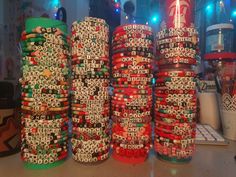 several stacks of bracelets sitting next to each other on top of a table with christmas lights in the background