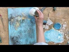 a person painting on a piece of wood with blue and white paint in the background