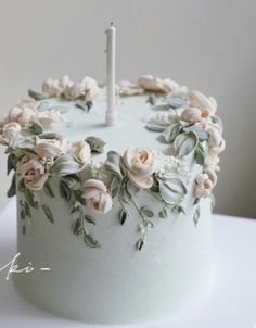 a white cake decorated with flowers and a single candle