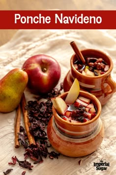 two cups filled with fruit and cinnamon on top of a table next to an apple