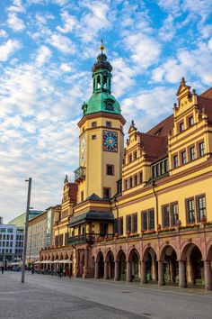 a large building with a clock on the top of it's tower in front of a cloudy blue sky