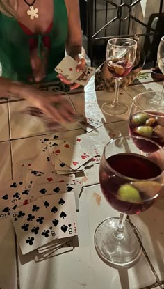 a woman sitting at a table with cards and wine glasses on top of the table