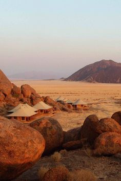 there are many tents in the desert with rocks and grass on the ground near by