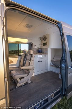 the interior of a camper van with its door open to reveal a kitchen area