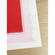 a piece of paper that is laying on top of a wooden table with red and white paint