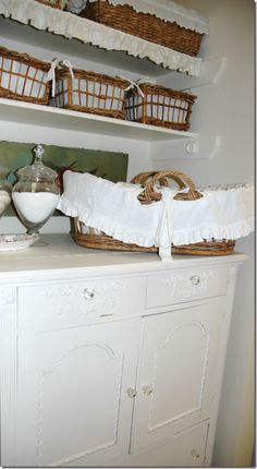 a white cabinet with baskets and dishes on it