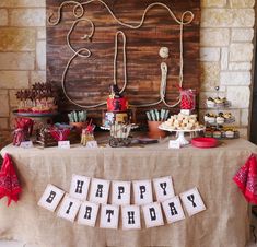 a happy birthday sign is displayed on a table with cupcakes and desserts