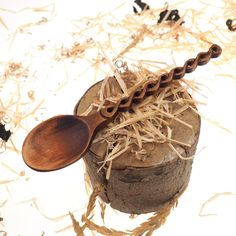 a wooden spoon sitting on top of a piece of wood next to shredded up straw