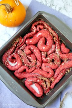 a pan filled with red food next to an orange pumpkin