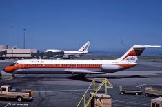 an orange and white jet airliner sitting on top of an airport tarmac next to other planes