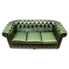 a green leather couch sitting on top of a white floor