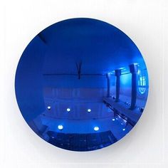 a circular mirror reflecting the inside of a building with blue lights on it's sides