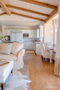 a living room filled with furniture next to a kitchen and dining room table on top of a hard wood floor