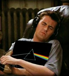 a man laying in a chair holding a laptop with the dark side of the moon on it